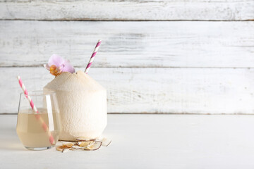 Fresh coconut and glass of water on light wooden background