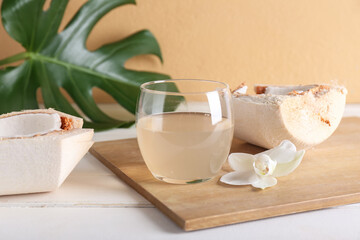 Glass of tasty coconut water on light wooden background