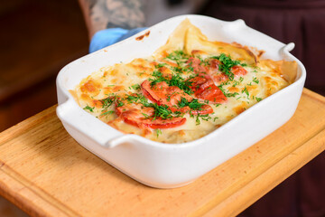 Close-up of a traditional lasagna made with minced beef bolognese sauce served by waiter in restaurant or diner.