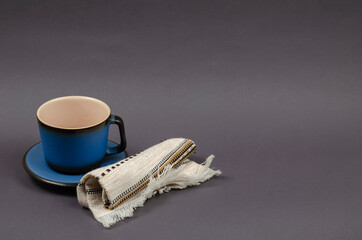 Blue cup and saucer and a rolled ethnic napkin on a gray background.