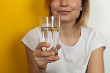 glass of clean drinking water in female beautiful hands. Beautiful young blonde girl with a glass of vodzha in her hands