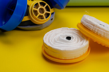 New replacement filters and Industrial respirator on yellow background.