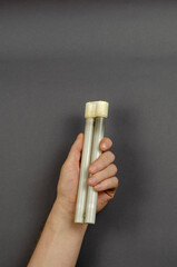 A hand holds a burnt-out  fluorescent lamp on a gray background.
