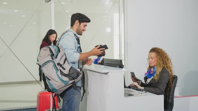Caucasian male passenger handing phone to staff for check-in scanning.