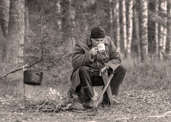 landscape with a forester in the woods by the fire, a worker drinks tea and warms up by the fire, sepia