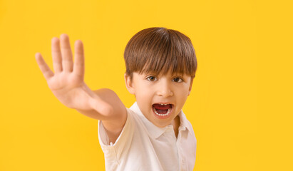 Cute little boy waving hand on color background