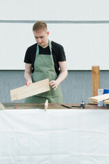 Carpenter working with wooden plate. Carpenter working with wooden plank. The young man is working near his house. 