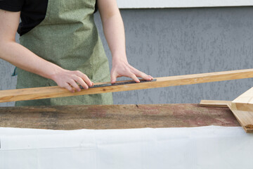 Carpenter working with wooden plate. Carpenter working with wooden plank. The young man is working near his house. 