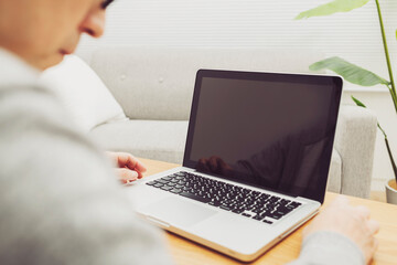 自宅のリビングでテレワークしている男性