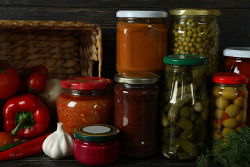 Jars with different canned food on wooden background