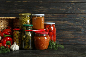 Jars with different canned food on wooden background