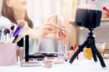 Concept Influencer blog cosmetics. Young woman beauty blogger recording makeup tutorial video stream on phone