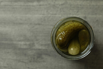 Jar of pickled cucumbers on gray background, top view