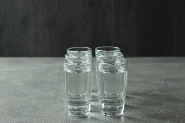 Shots with vodka on gray background, space for text