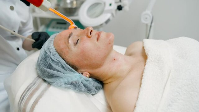 Facial massage of a patient in a cosmetic spa salon using a device with a high-frequency current