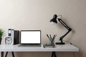 Modern contemporary workspace with blank screen laptop computer with office supplies and stationery on office desk on white background for copy space. Home office workplace concept.