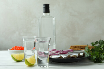 Shots of vodka and tasty snacks on white wooden table