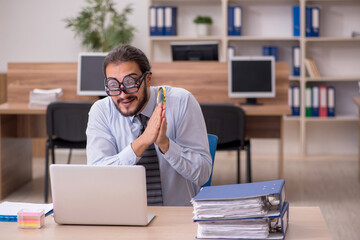 Obraz premium Young funny businessman employee working at workplace