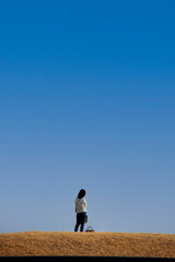 Naklejka na ściany i meble 綺麗な青空と公園で散歩している若い女性の姿