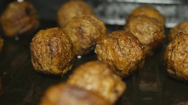 fried meatballs on a baking sheet are illuminated by a movement of light in the dark. Shadows change. Dolly shooting. Close-up