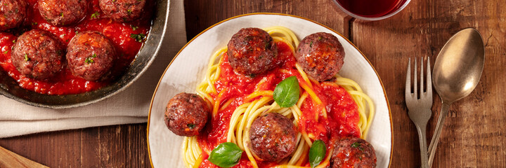 Meatballs with pasta, overhead flat lay panorama on a rustic wooden background