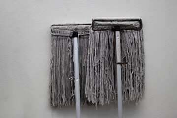 Dirty and old mops cleaning against the sun on the outdoor concrete wall