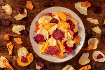 Vegetable chips, overhead flat lay shot on a dark rustic wooden background
