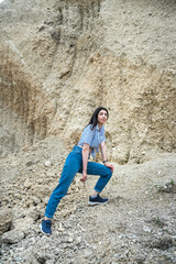 Pretty woman in casual clothes poses in sand canyon, relax at nature in summer time