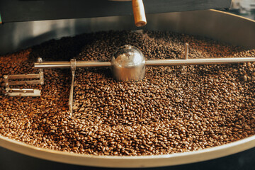 The freshly roasted coffee beans from a large coffee roaster being poured into the cooling cylinder. Motion blur on the beans