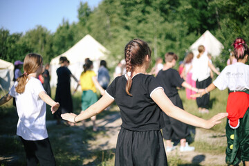 Group of children stretching hands, doing morning exercises sport outdoors in nature in a children's summer camp
