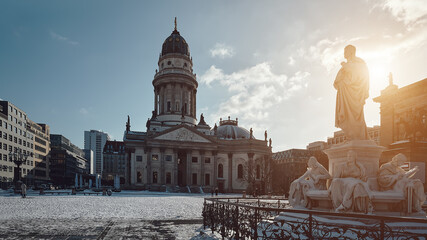 Gendarmenmarkt square in Berlin with German Cathedral, or Deutsche Dom in German. The Schiller Monument, historic statue of Friedrich Schiller in front. Cold winter day with blue sky and snow. © tilialucida