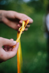 Handmade ribbon orange-yellow bracelet girl holding in her hands on a background of green grass