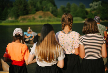 Group of children stand from backs and cheer for their friends at summer camp. Background of nature, weather before the storm