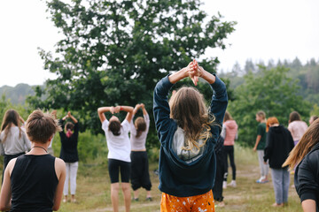 Group of children doing morning exercises yoga-sport outdoors in nature in a children's summer camp