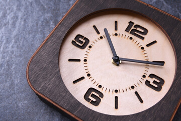Naklejka na ściany i meble Wooden clock made in hand on wooden background. Close-up. Place for text.
