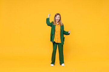 Full length little blonde excited happy expressive kid girl 12-13 years old in casual clothes do winner gesture clench fist isolated on yellow background children portrait Childhood lifestyle concept