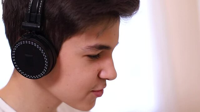 Process of teenage boy puts on headphones befour starting play games. Side view of boy preparing for gaming. Close up