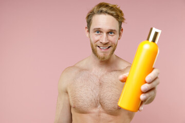 Smiling attractive bearded naked young man 20s perfect skin hold empty blank bottle of shampoo...