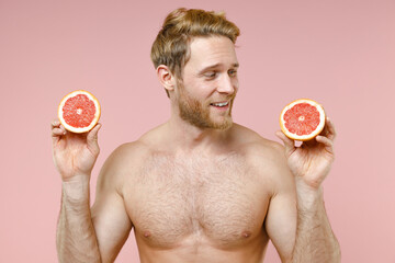 Smiling bearded naked young man 20s years old perfect skin hold halves of fresh grapefruit isolated...