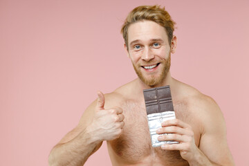 Smiling bearded naked young man 20s years old perfect skin hold chocolate bar showing thumb up...