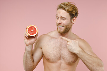Smiling bearded naked young man 20s years old perfect skin point index finger on half of fresh...