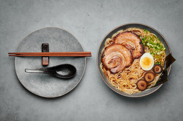 A Shoyu Ramen in gray bowl on concrete table top. Japanese cuisine meat noodle soup with chashu pork. Asian food. Top view