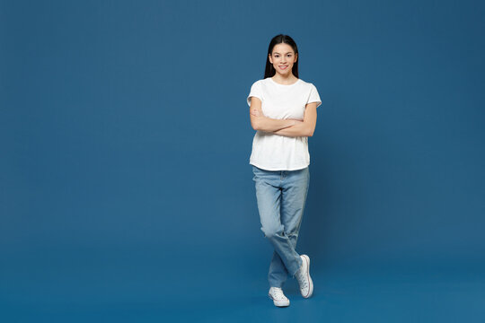 Full length of young smiling confident attractive beautiful latin woman 20s wearing white casual basic t-shirt hold hands crossed folded look camera isolated on dark blue background studio portrait.