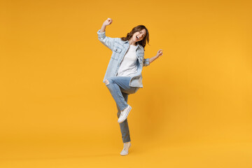 Fototapeta na wymiar Full length of young overjoyed excited fun student happy woman 20s in denim shirt white t-shirt do winner gesture clench fist celebrating dancing isolated on yellow color background studio portrait