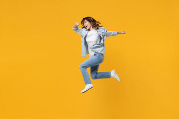 Naklejka na ściany i meble Full length of young excited fun expressive fast sporty student woman 20s wear casual stylish denim shirt white t-shirt run jump high hurrying up scream isolated on yellow background studio portrait