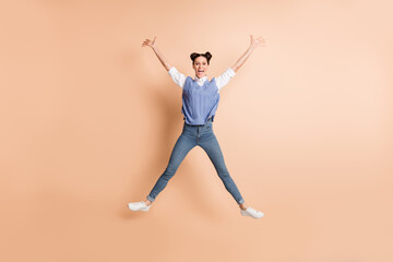 Fototapeta na wymiar Full size photo of brunette optimistic lady jump wear white shirt blue vest jeans sneakers isolated on beige color background