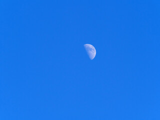 View of the moon on a clear winter day. Blue sky. Partial Moon visible