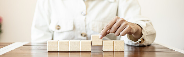 The business woman grasped the rectangular wooden blocks in a row, the square wooden blocks arranged on the table by the businesswoman.