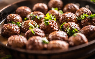 Detail of Swedish meatballs, kottbullar, in a pan topped with fresh parsley