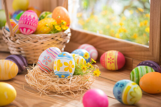 Happy Easter day colorful eggs in nest and flower on wood with window lighting